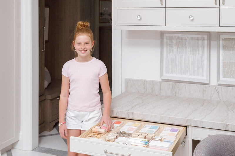 Young girl standing next to an organized craft drawer.