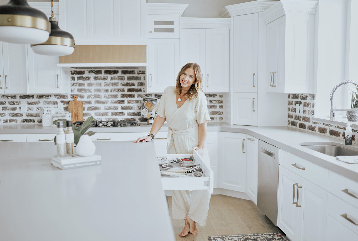 Woman smiling in her kitchen next to an open and organized utensil drawer.