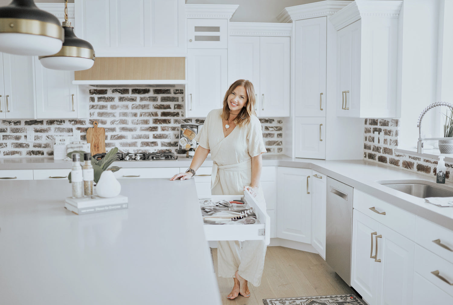 Woman smiling in her kitchen next to an open and organized utensil drawer.