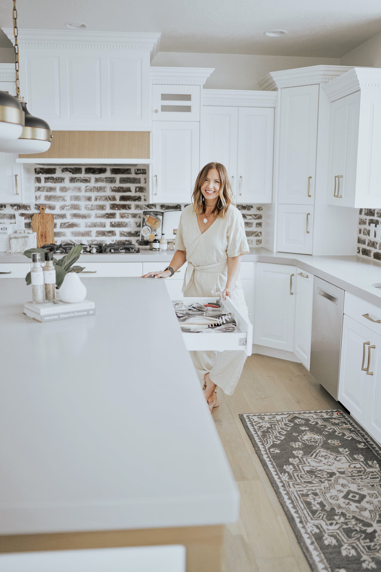 Woman gleefully opens an organized kitchen utensil drawer.