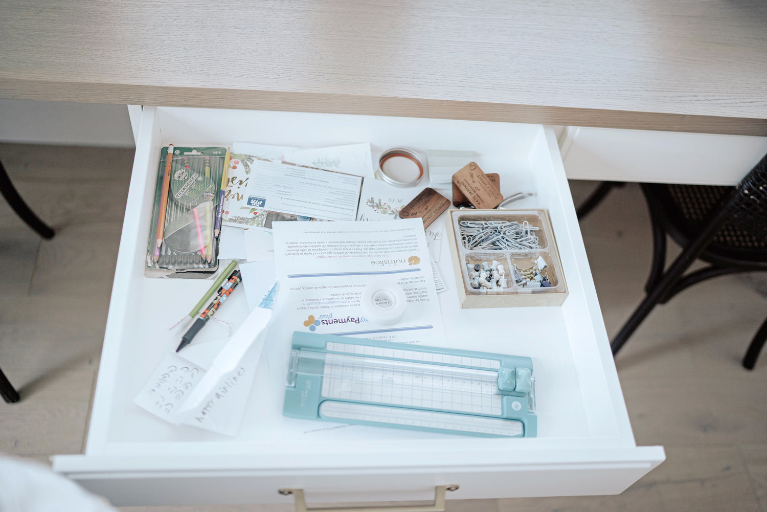 Messy drawer filled with a variety of papers and craft supplies.