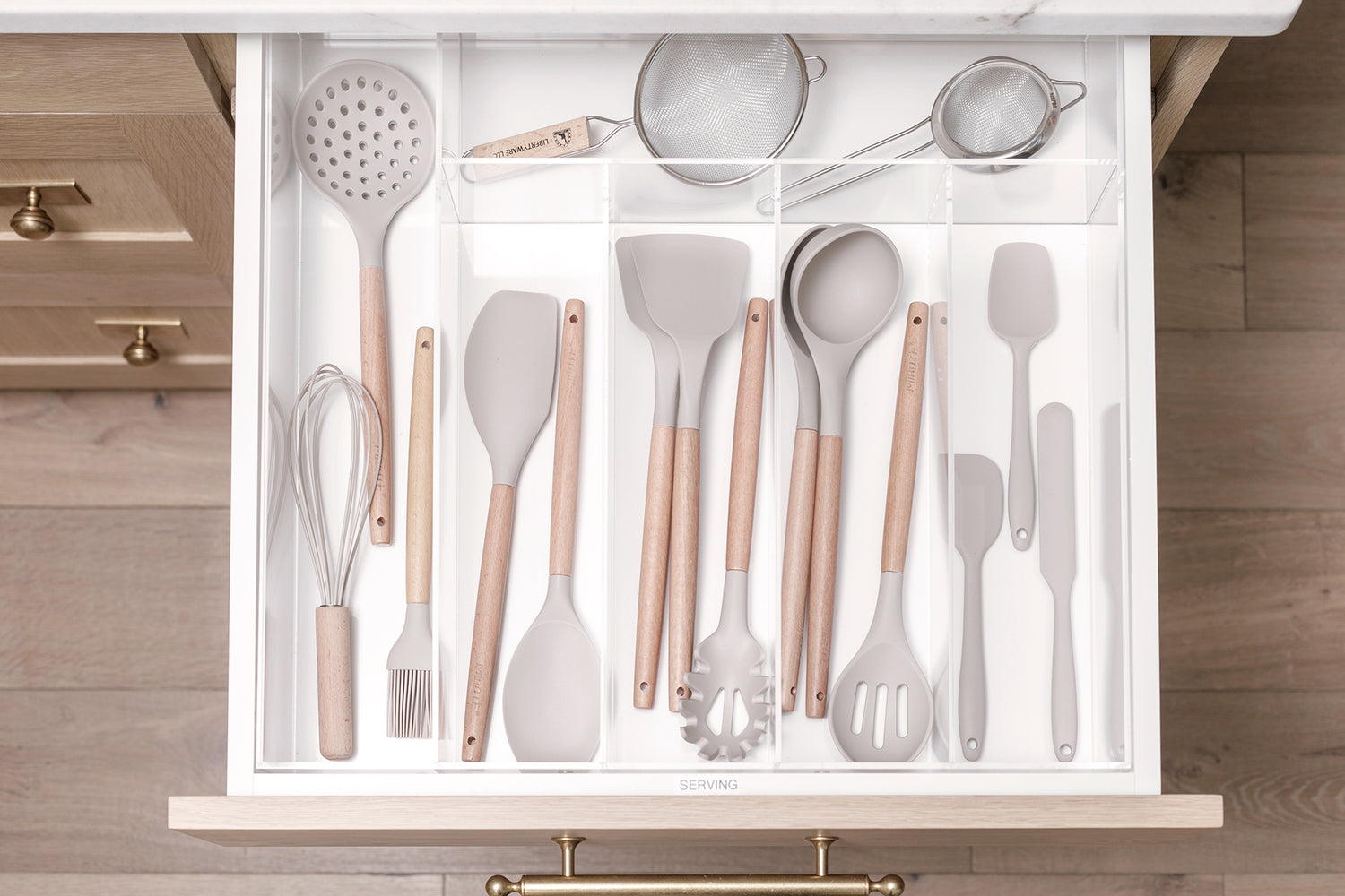 Neutral-toned kitchen drawer opened to show a delightfully organized collection of utensils.