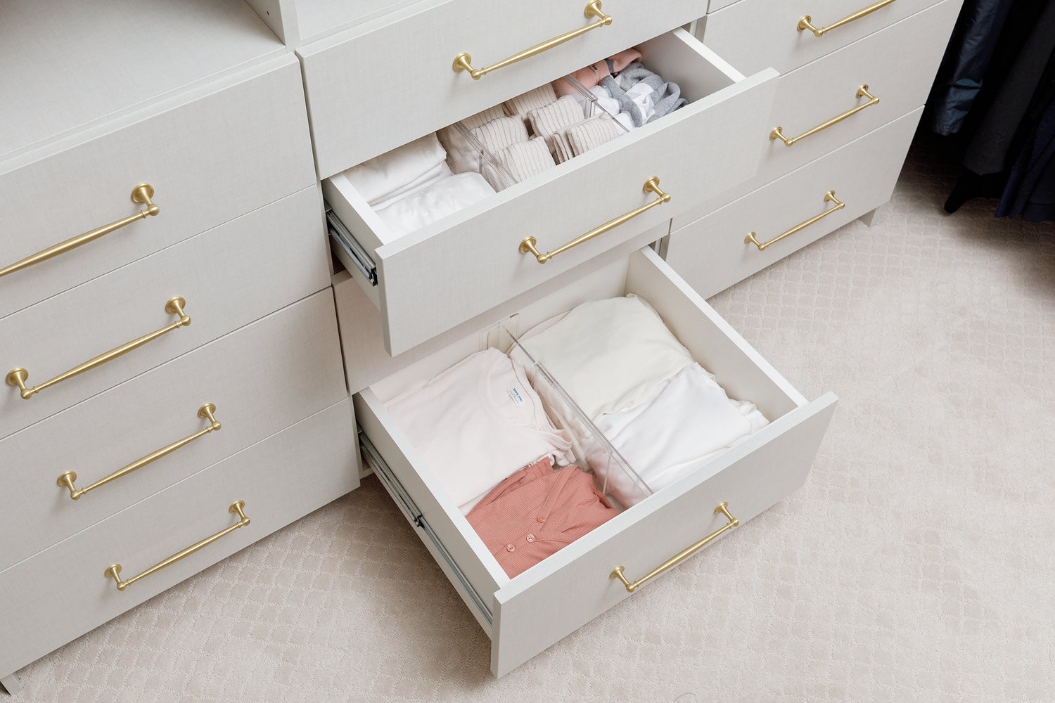 Closet drawers opened to show Acrylic Drawer Dividers at work containing a variety of clothing items.