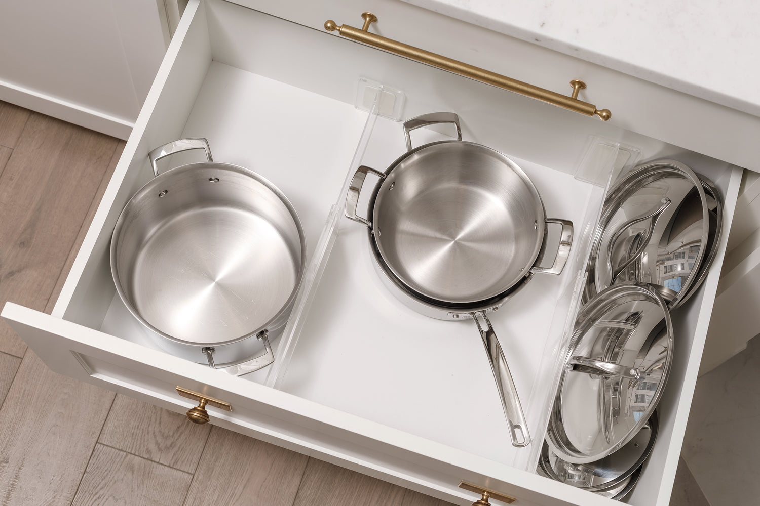 Two Acrylic Drawer Dividers creating three separate spaces for pots, pans, and lids in a drawer.