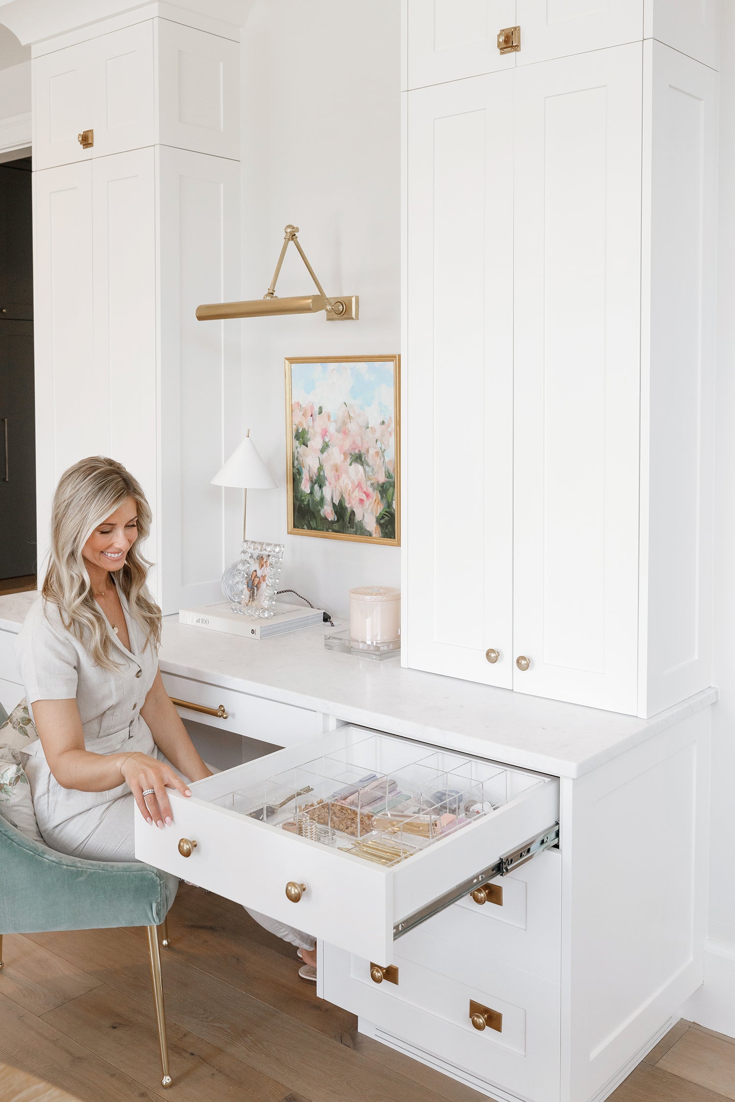 Woman smiling down at a beautifully organized desk drawer.