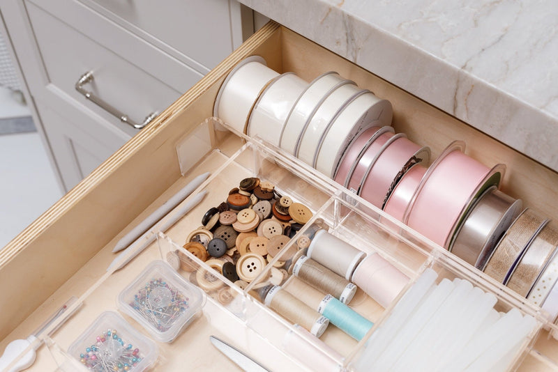 Close-up view of an acrylic Expandable Organizer containing a variety of craft supplies.