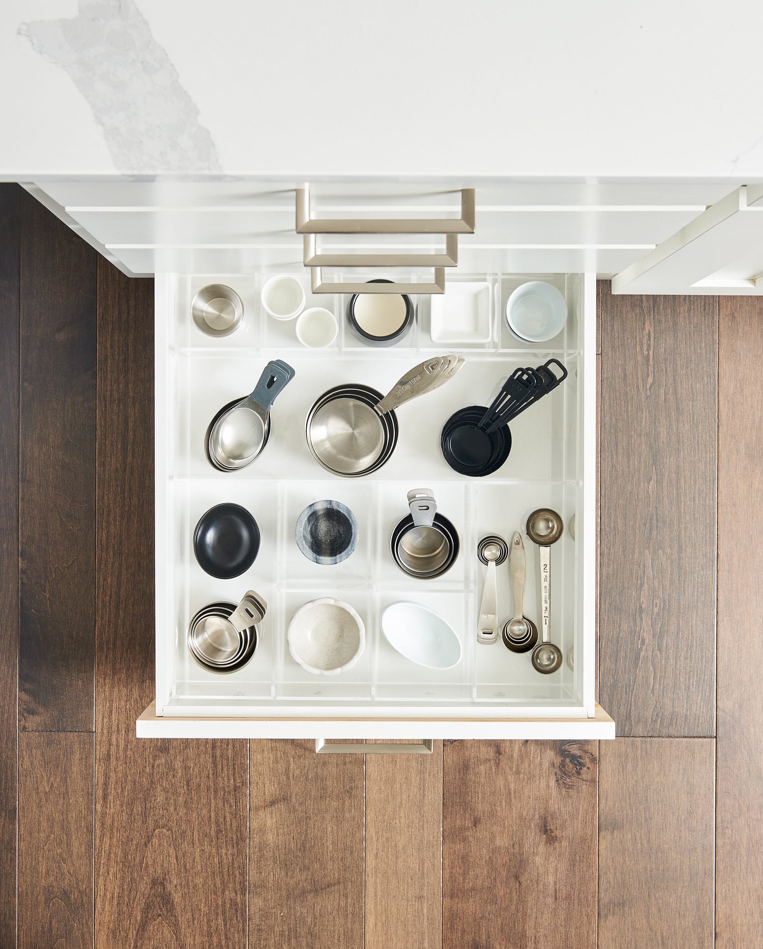 Top view of an organized kitchen drawer filled with measuring cups and spoons.