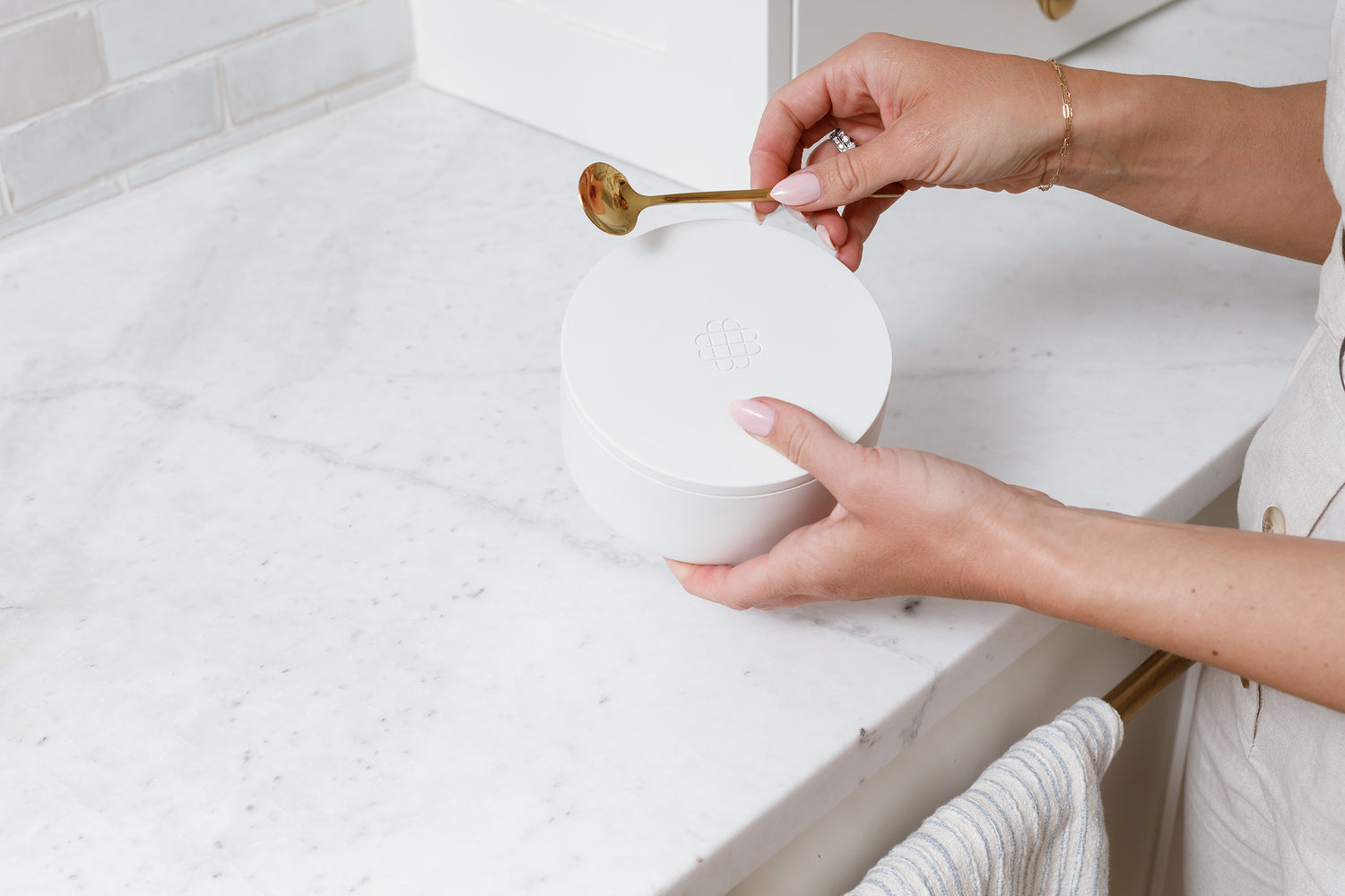 Hands holding a white Salt Container and mini golden spoon.