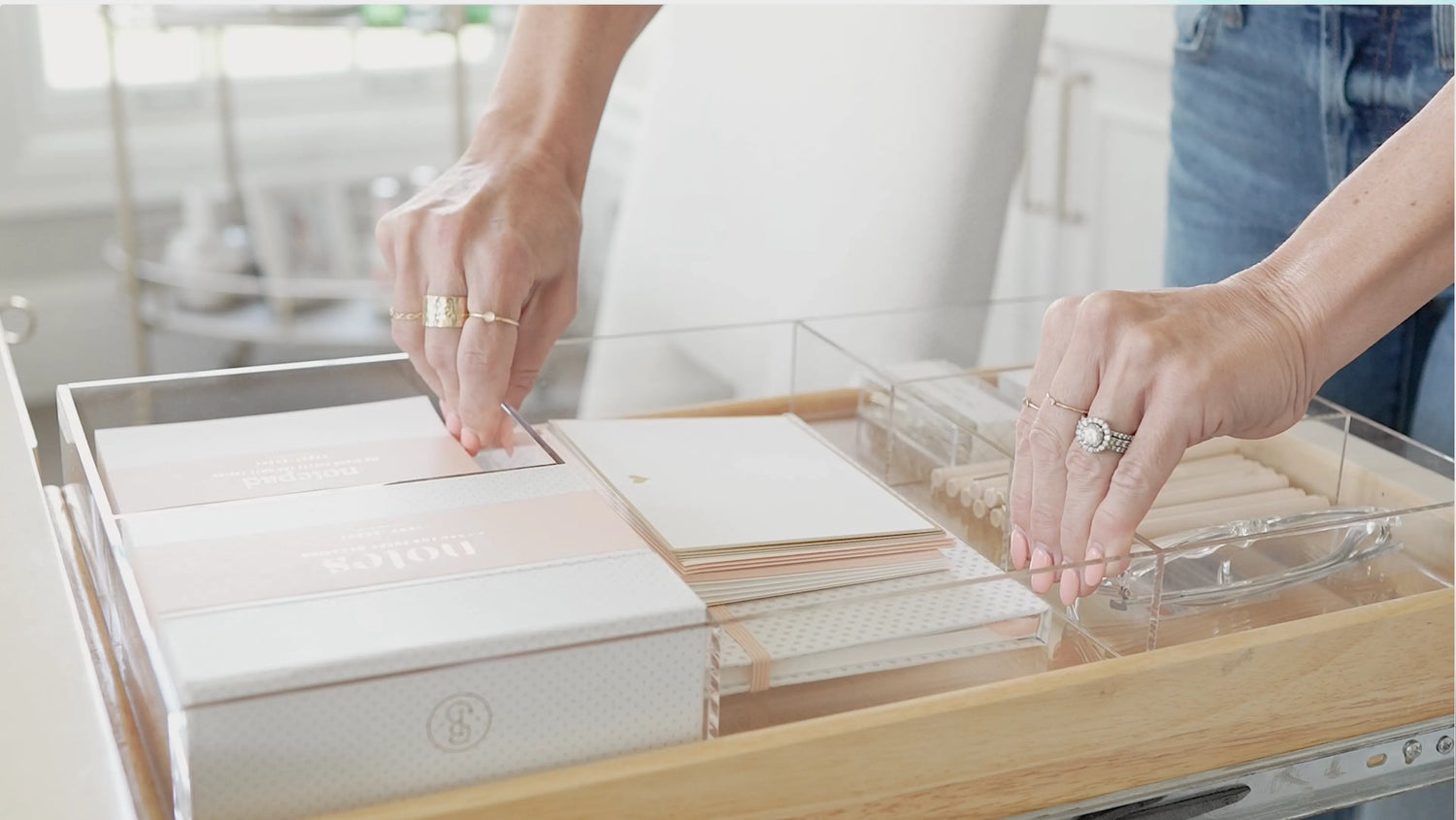 Woman installing a new fully stocked custom-fit drawer organizer with a variety of office supplies.