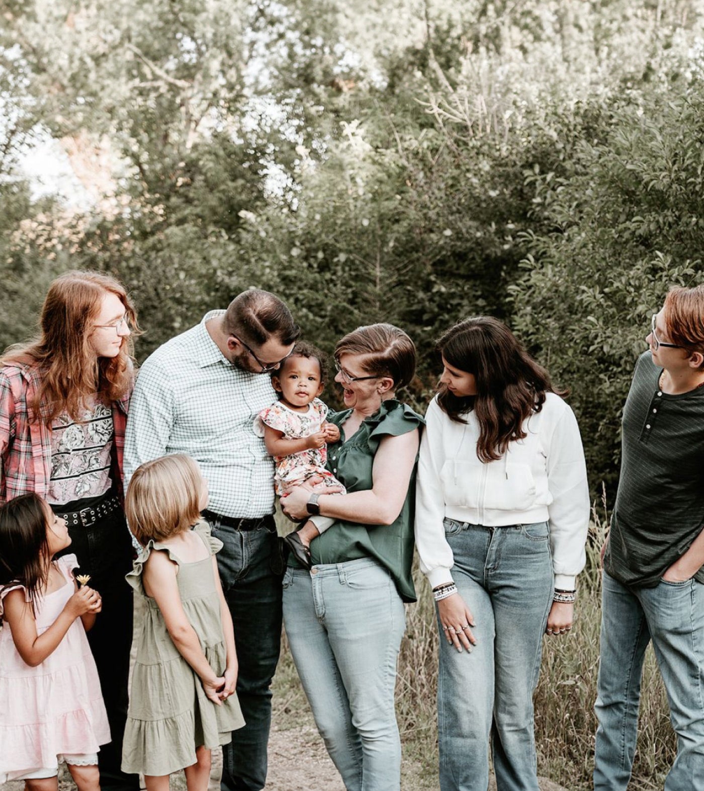 Adorable family photo with parents and kids focused on the baby in the middle.