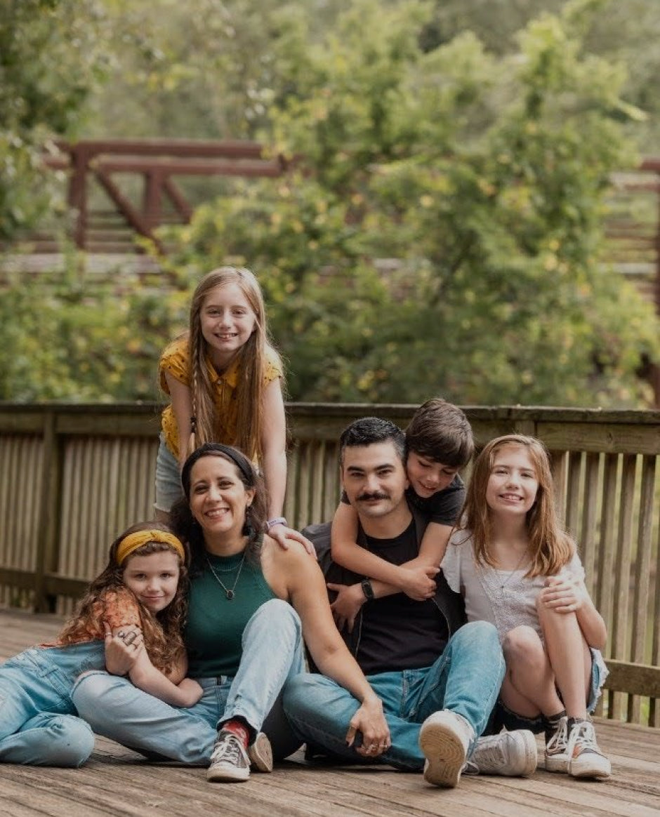 Darling family sitting close together for a picture on the deck. 