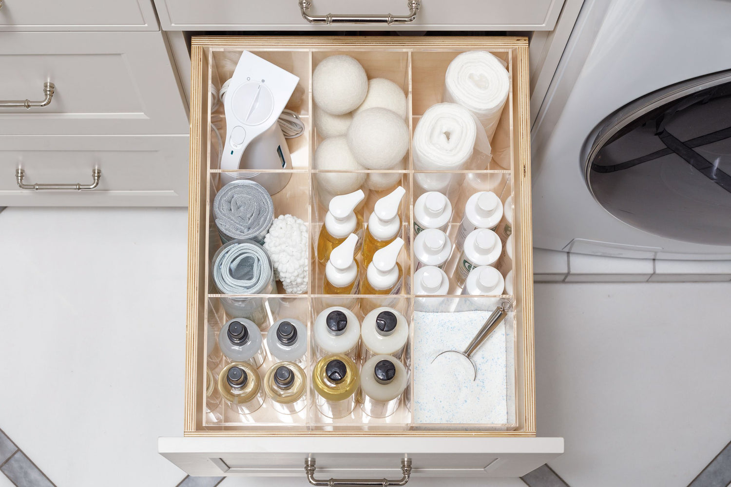 Organized laundry room drawer stocked with detergent, dryer balls, and soap. 