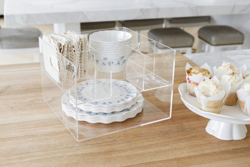 Acrylic Utensil Caddy holding dainty white and blue plates, bowls, and linen napkins.