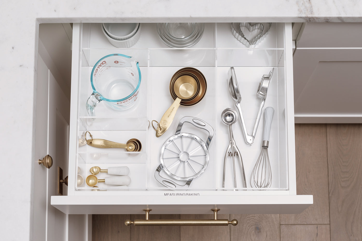 Baking tools and measuring utensils in an open kitchen drawer contained in a custom-fit organizer.