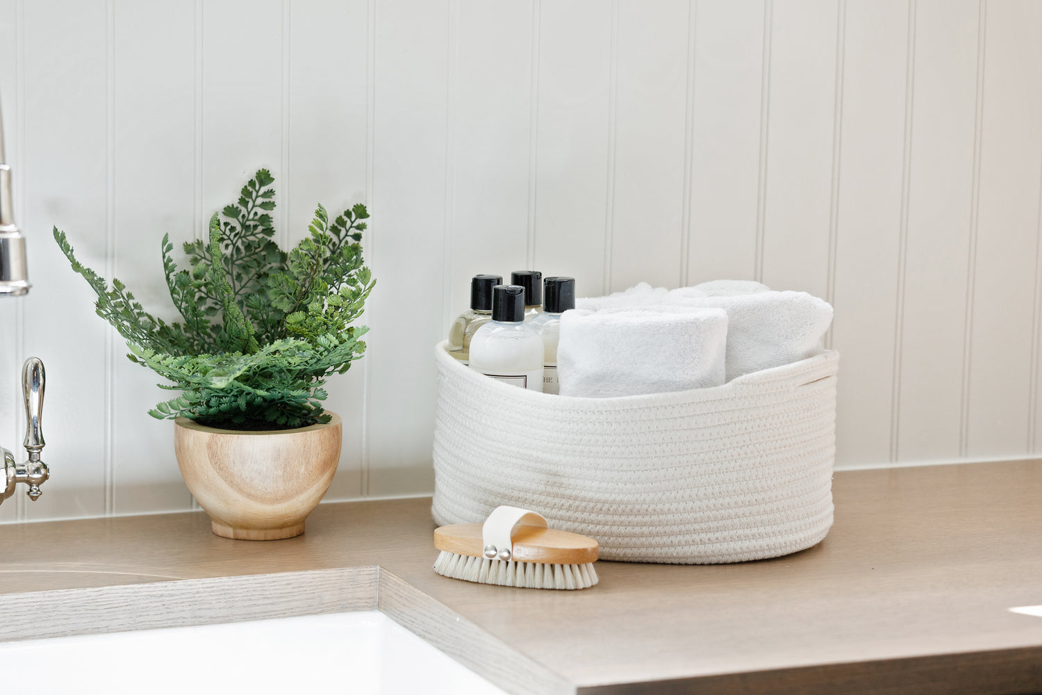 Laundry room counter top with a white Alpine basket filled with soap and towels.