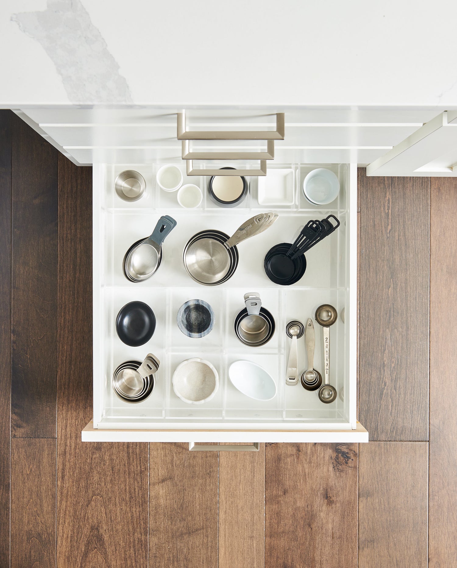 Top view of an organized kitchen drawer filled with measuring cups and spoons. 