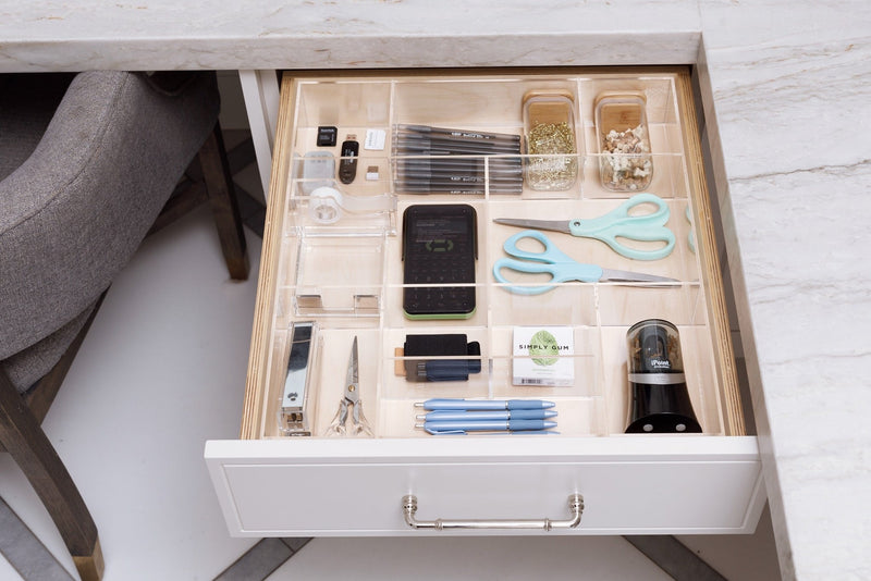Crystal clear acrylic drawer organizer in an office drawer holding essential products.
