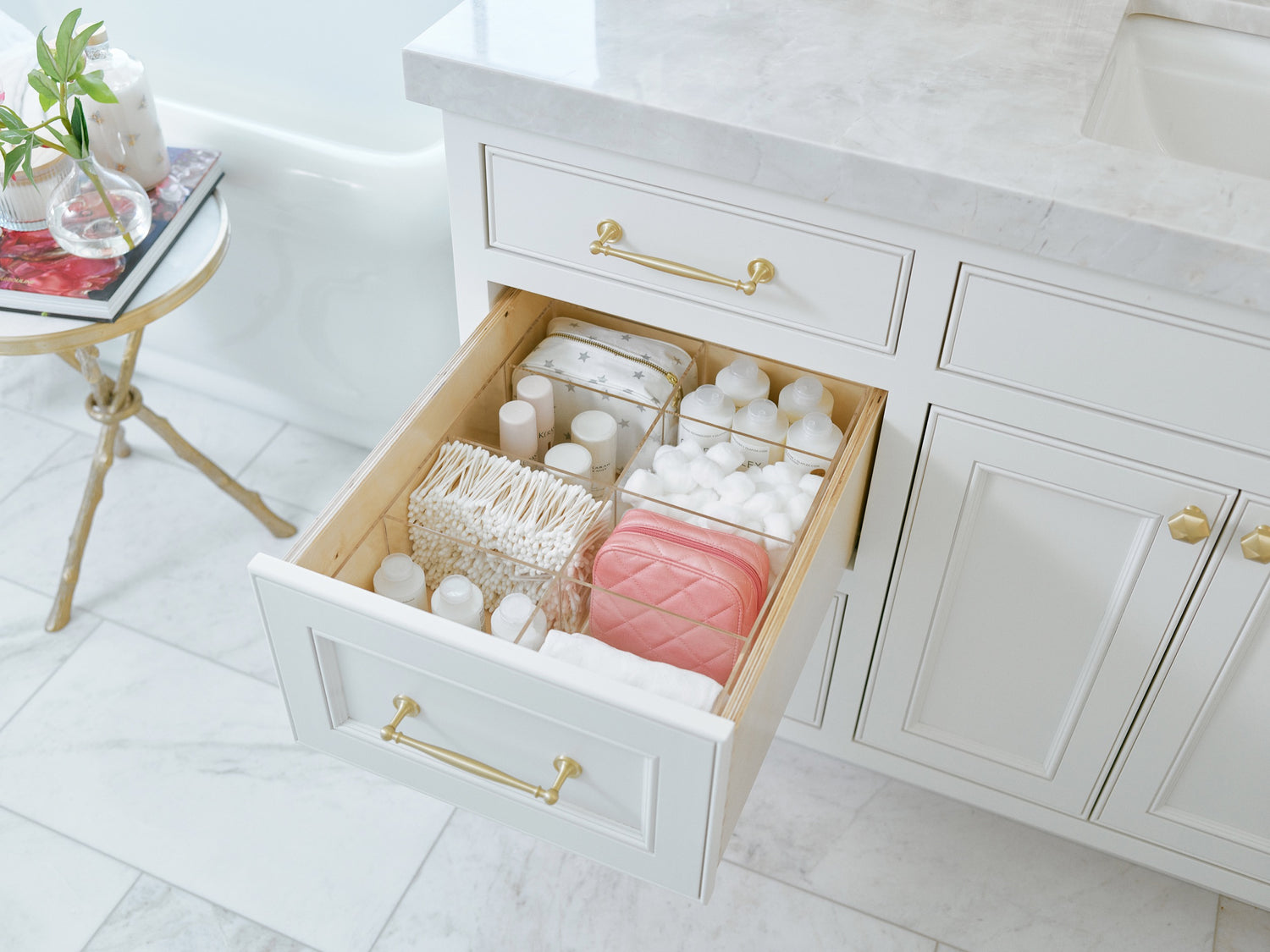 Open bathroom drawer stocked to the brim with essentials including cotton balls and swabs.