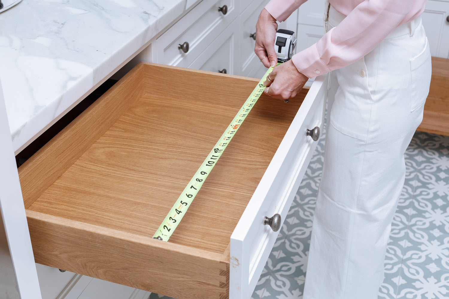 A woman measuring the width of her kitchen drawer. 