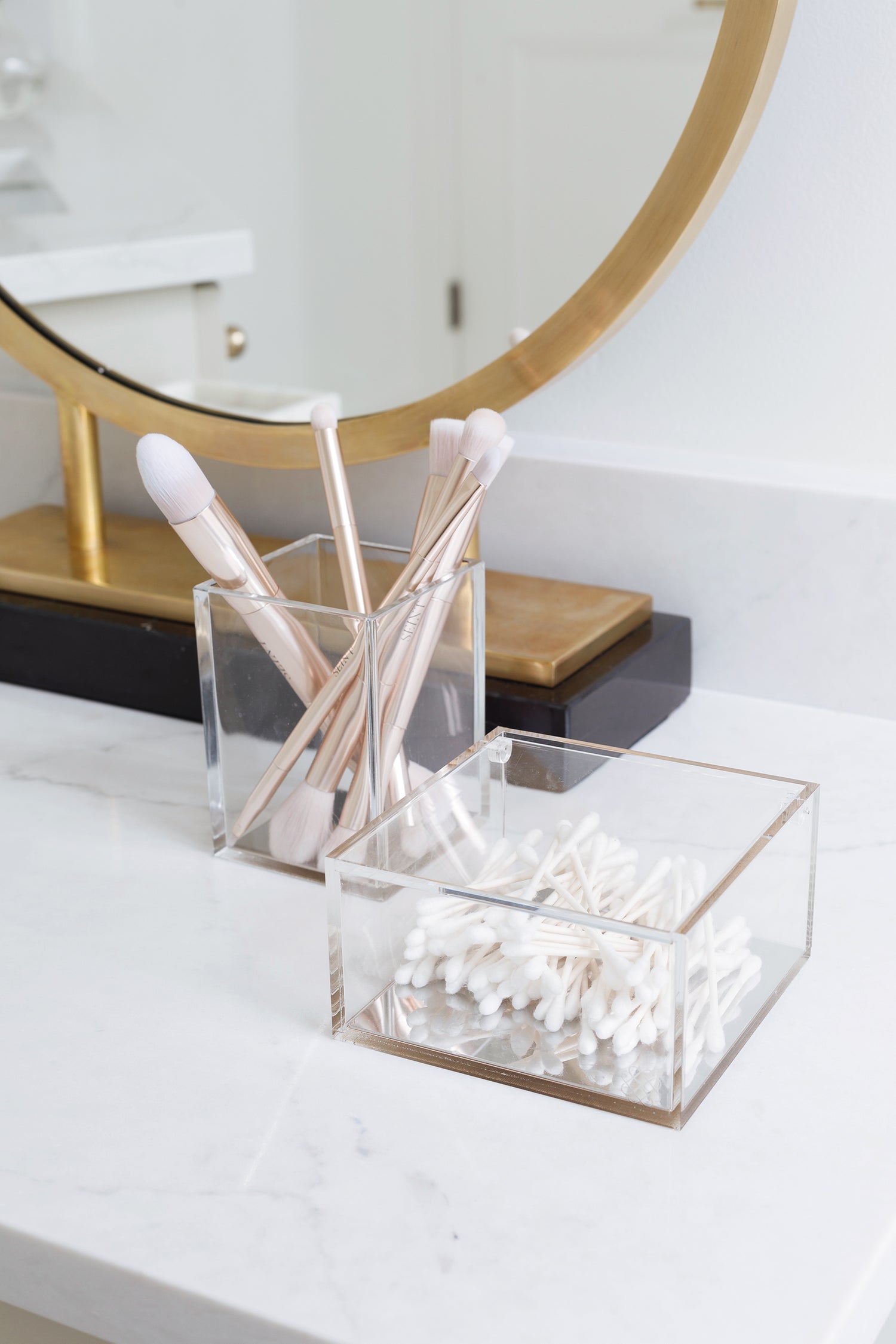 Makeup brushes and cotton swabs held in acrylic storage containers.