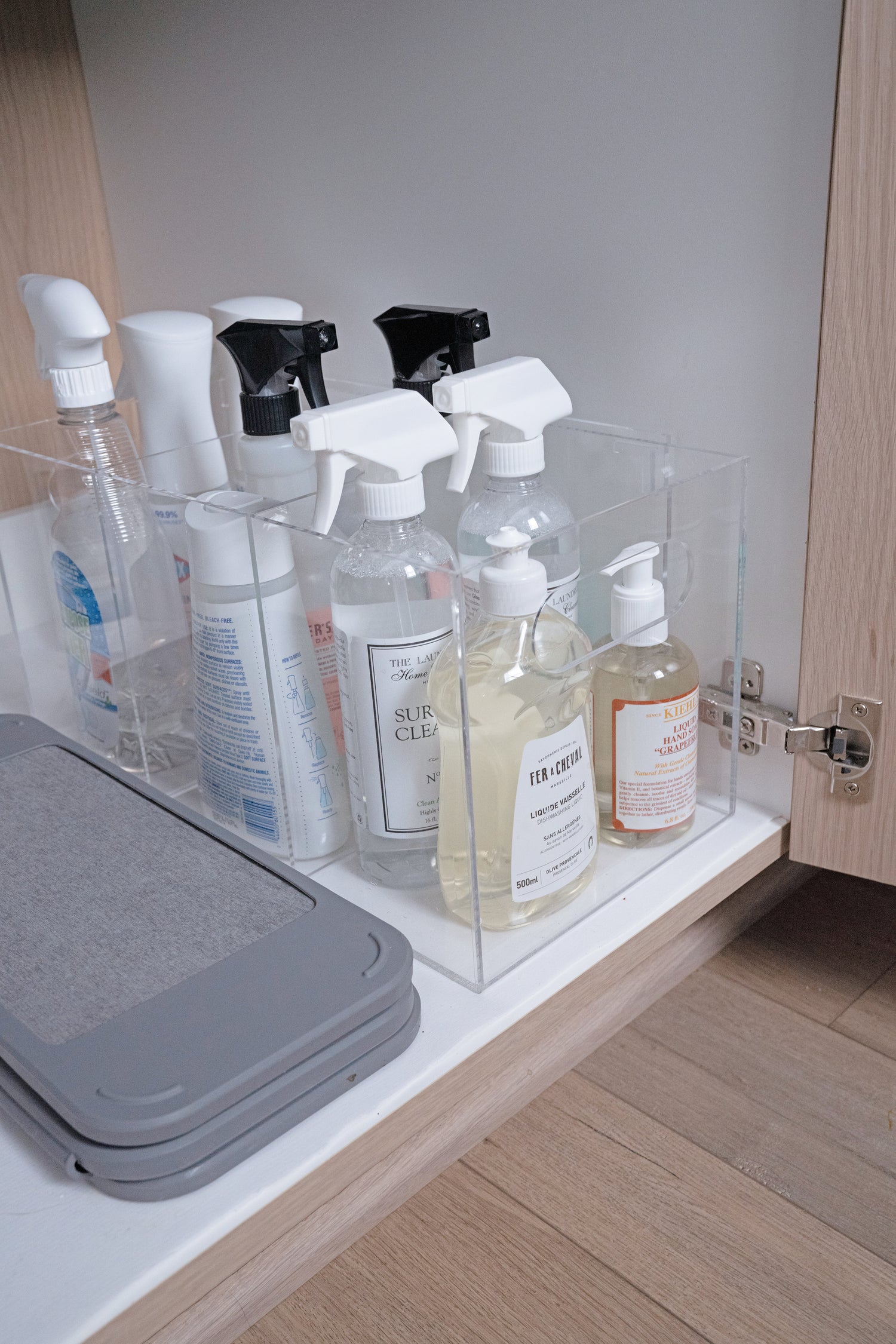 Cleaning supplies organized with a Remi Caddy and stored in a cabinet. 