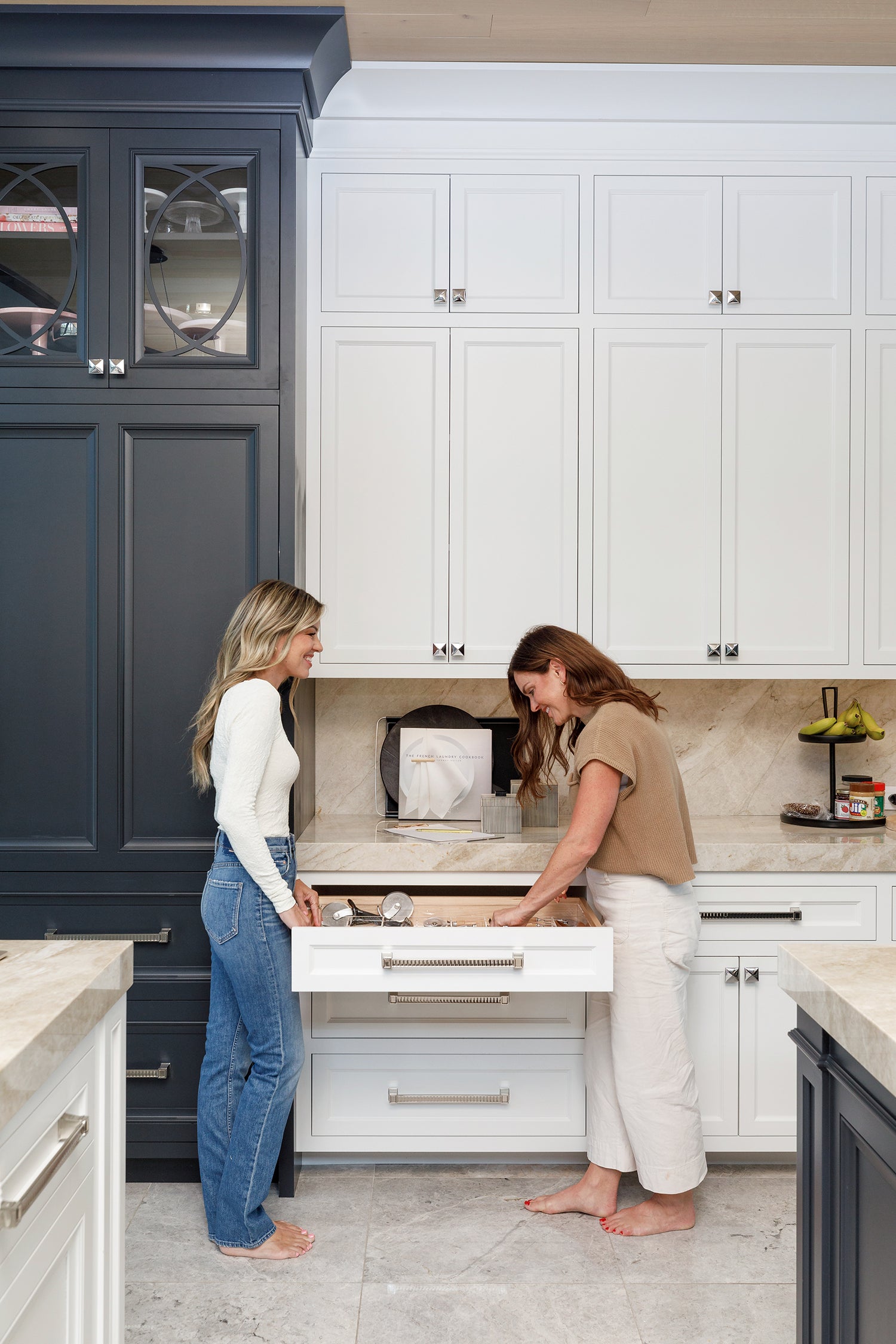 Two women admiring an organized kitchen drawer. 