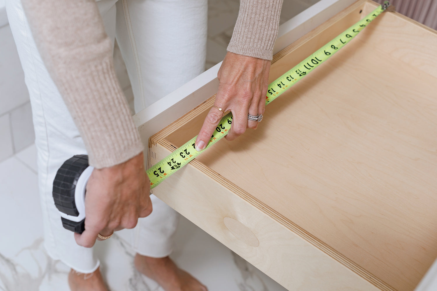 A woman measuring the width of one of her drawers.