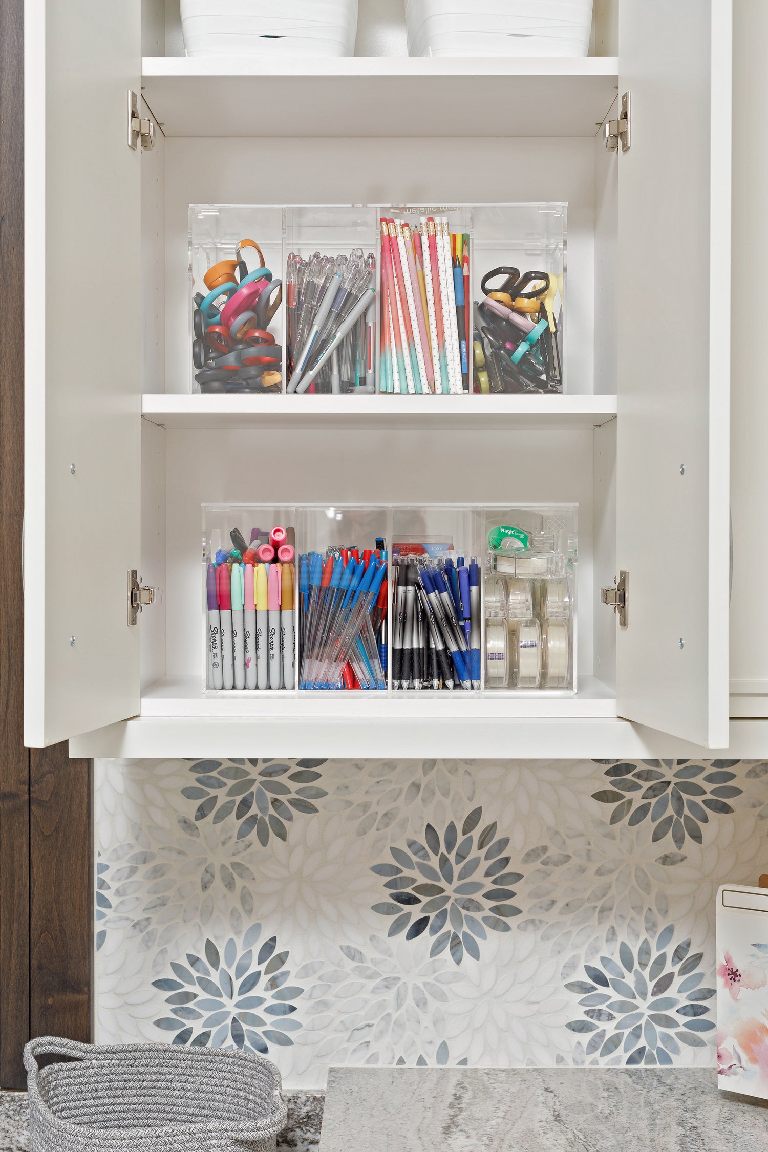 A cabinet filled with crafting supplies contained in clear acrylic organizers.
