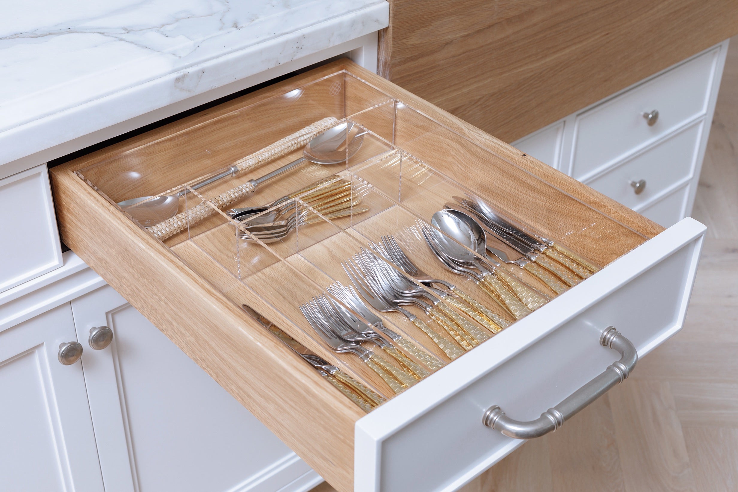 Drawer containing silverware organized in a clear acrylic organizer. 