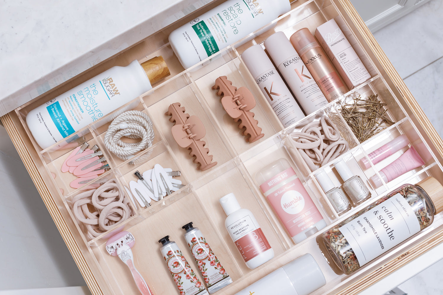 Immaculate bathroom drawer using a Sydney custom-fit organizer to contain products such as hair ties, nail polish, and lotion.