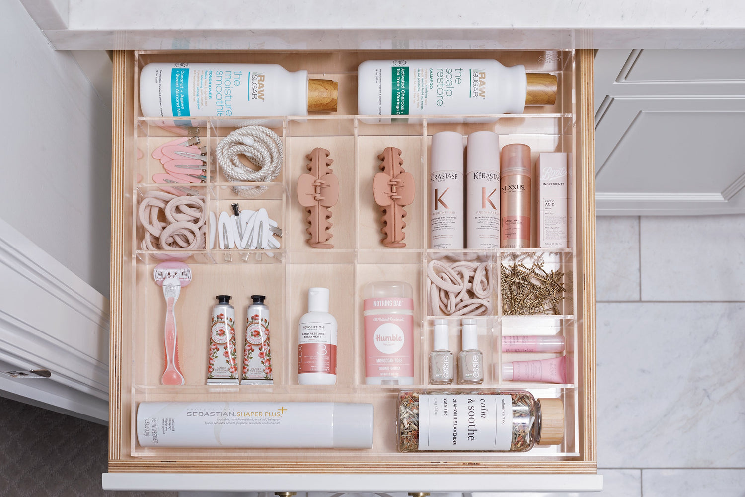 Immaculate bathroom drawer using a Sydney custom-fit organizer to contain products such as hair ties, nail polish, and lotion.