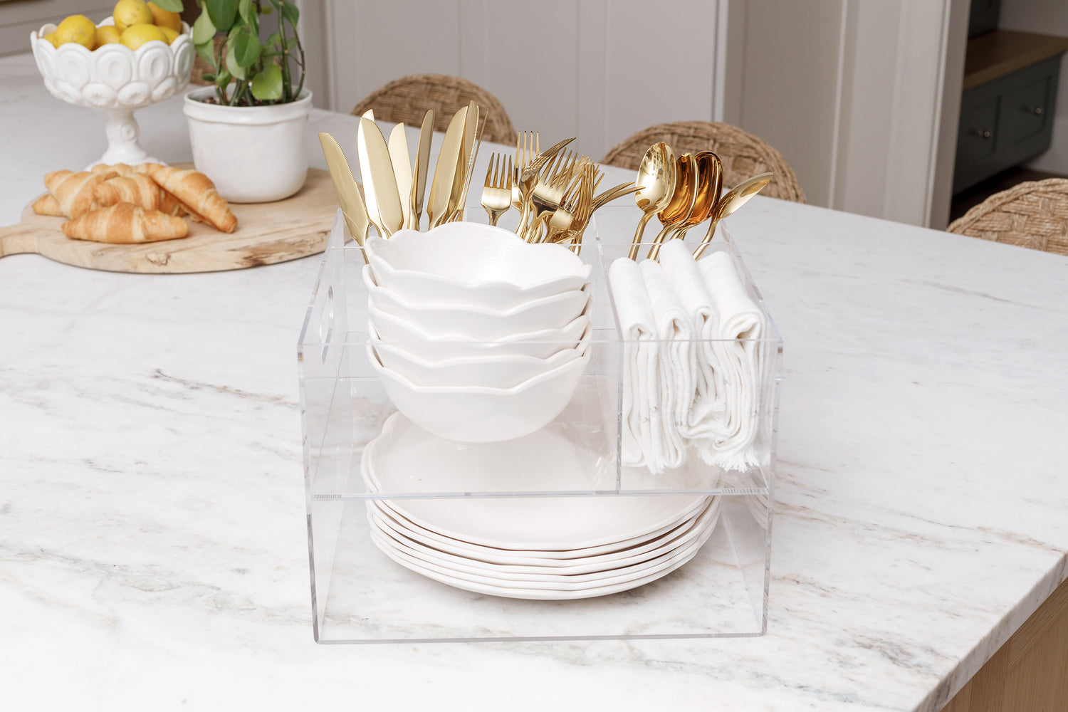 Acrylic Utensil Caddy sitting on the counter fully stocked with gold cutlery, white dishes, and linen napkins.