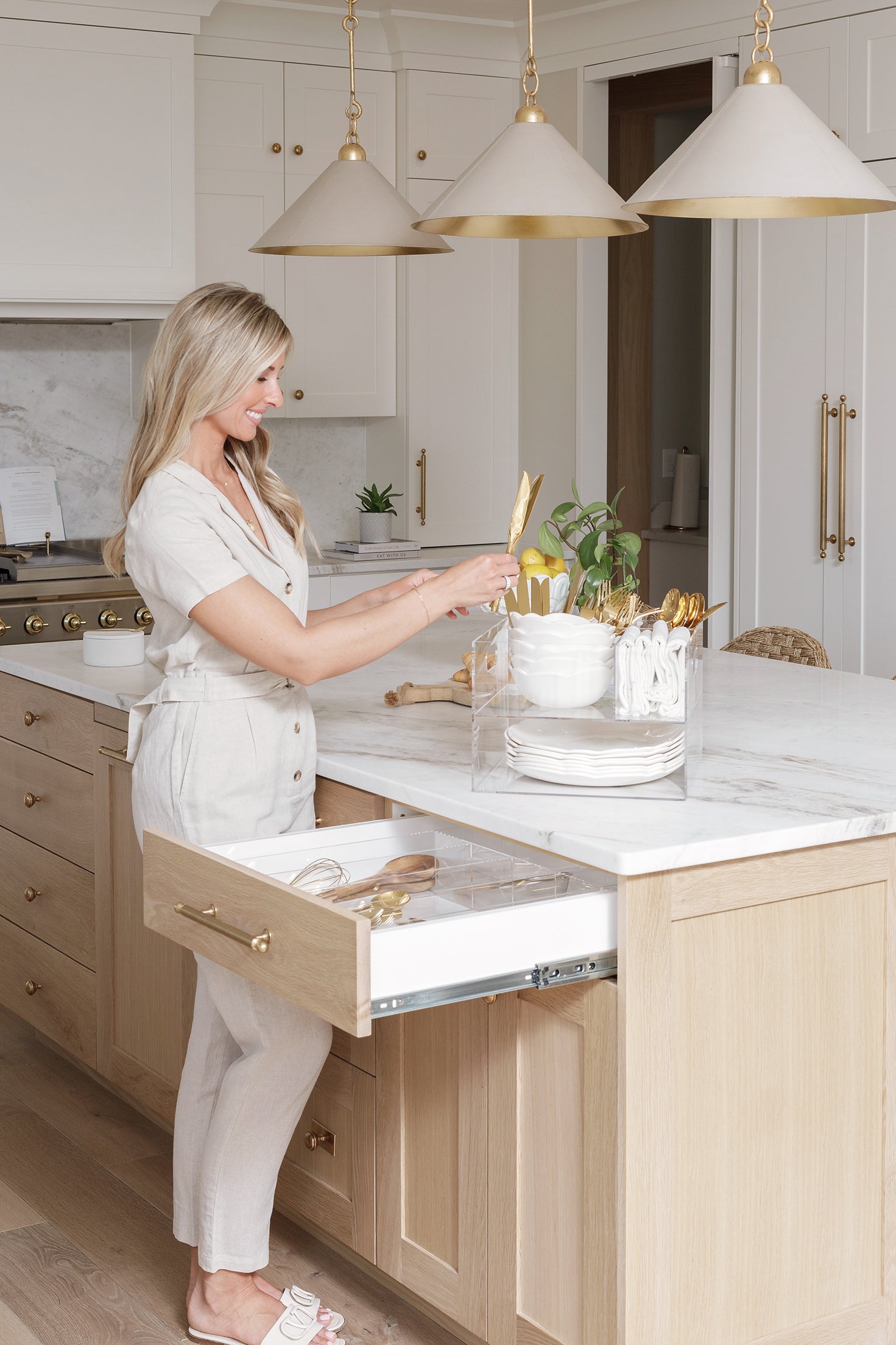 A woman stocks the Acrylic Utensil Caddy with gold cutlery from her kitchen utensil drawer.